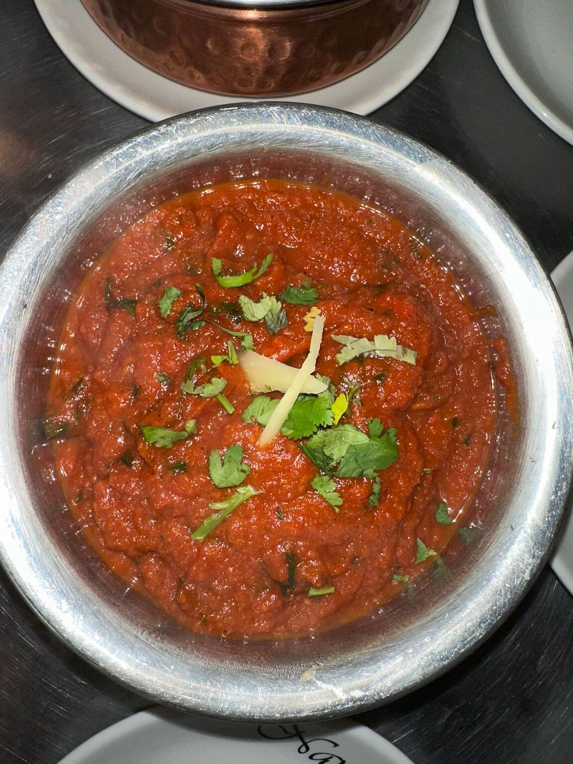  A deep red Bhuna curry garnished with fresh ginger and coriander in a silver 
bowl at MariGold restaurant, Kilmacolm. 